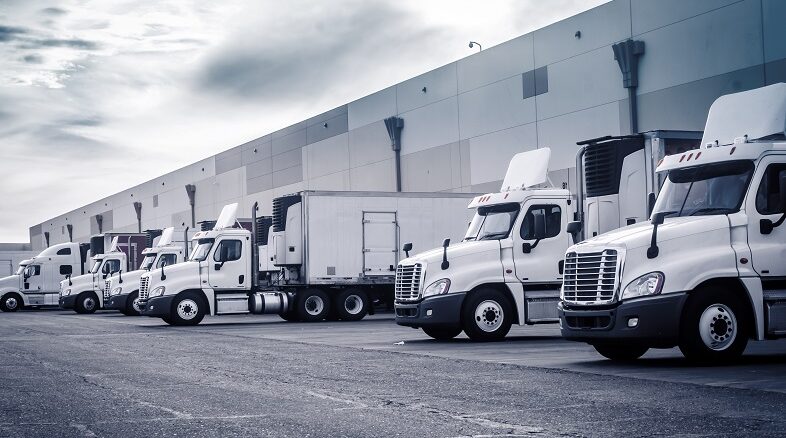 Delivering or Supply concept image. Trucks loading at facility.