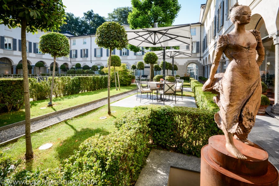 Statue of a woman, box hedge, topiaries and sitting areas in the courtyard at Four Seasons Milano