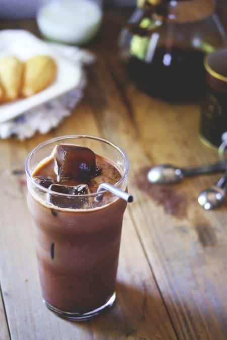 A cup of iced coffee sitting on top of a wooden table
